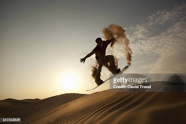 man sand boarding in desert - dubai stock-fotos und bilder