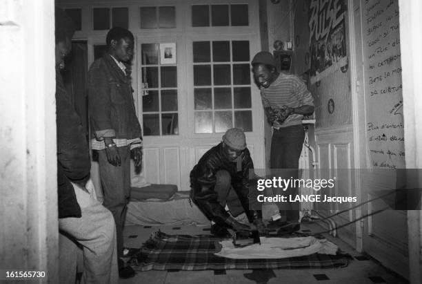 Squat And Squatters In Paris And Suburbs. Juin 1983, à PARIS, squatters d'origine africaine repassant le linge à même le sol dans un appartement...