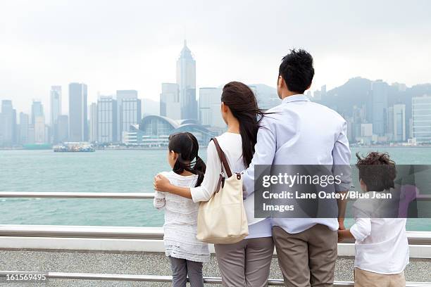 young family enjoying the beautiful scenery of victoria harbor, hong kong - hong kong harbour stock pictures, royalty-free photos & images