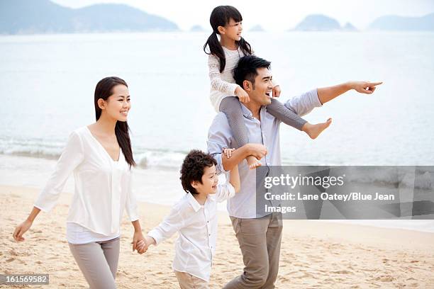 happy young family strolling on the beach of repulse bay, hong kong - hong kong family stockfoto's en -beelden