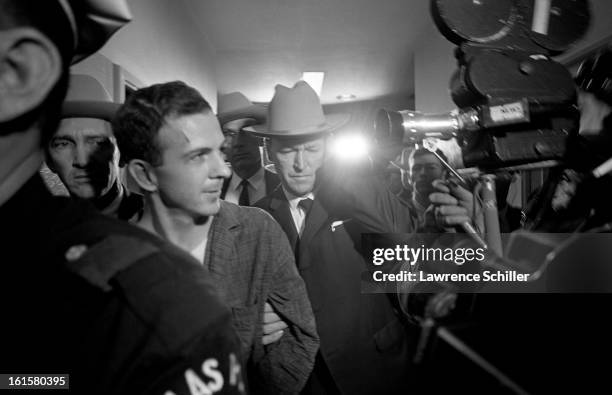 Crowded by police and members of the press, the accused assassin of President John F. Kennedy, Lee Harvey Oswald , is taken down the hall on the...