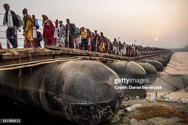 Hindu pilgrims walk across a pontoon bridge as others bathe on the banks of Sangam, the confluence of the holy rivers Ganges, Yamuna and the mythical...