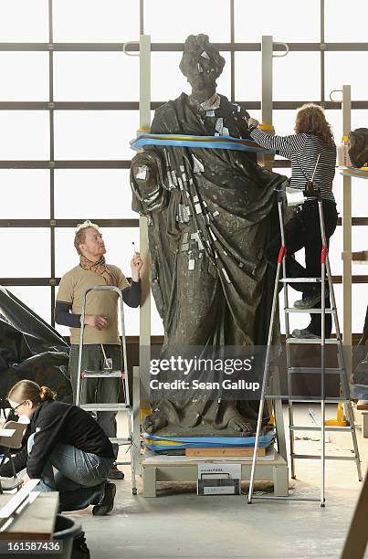 Stone restorers Frauke Herlyn and Anton Gruber attach thin sheets of tin to an original sculpture to prepare it for the creation of a casting mould...