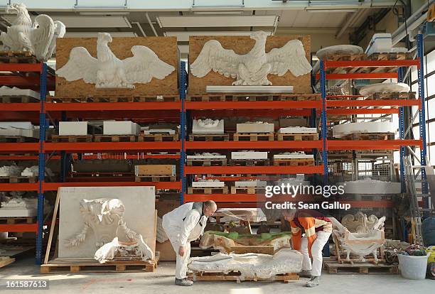 Artisans move a silicon mould as plaster cast facade elements lie stored on shelves behind at the Schlossbauhuette studio where a team of sculptors...