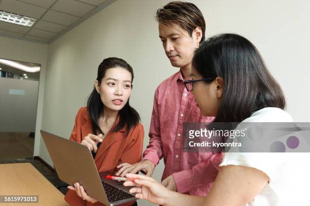 asian female interacting with her colleagues - southeast asian ethnicity stock pictures, royalty-free photos & images