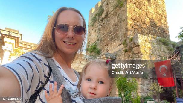 woman with baby girl make selfie while traveling in the old city of antalya, turkey and exploring the famous sightseeing hadrian's arch - art of the vintage selfie stockfoto's en -beelden