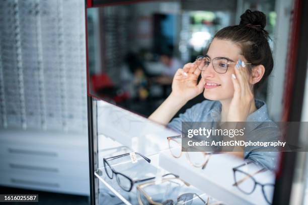 woman at the optician trying on glasses. - visual merchandise stock pictures, royalty-free photos & images