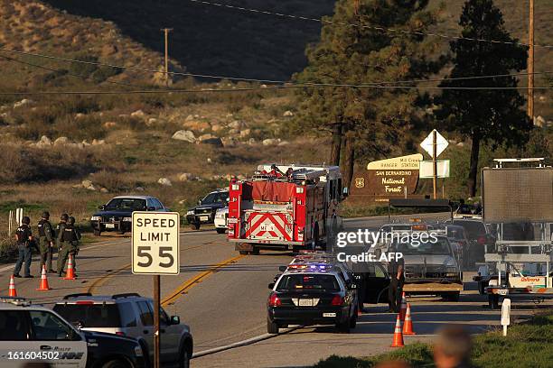 Firefighters pass a roadblock on Highway 38 toward the Big Bear Lake as a standoff with the ex Los Angeles police officer believed to now be a...