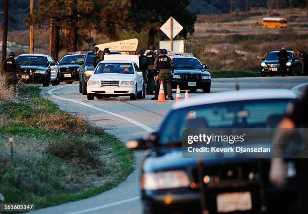 Police search cars at a blockade as they come down off the mountain during a manhunt for the former Los Angeles Police Department officer Christopher...