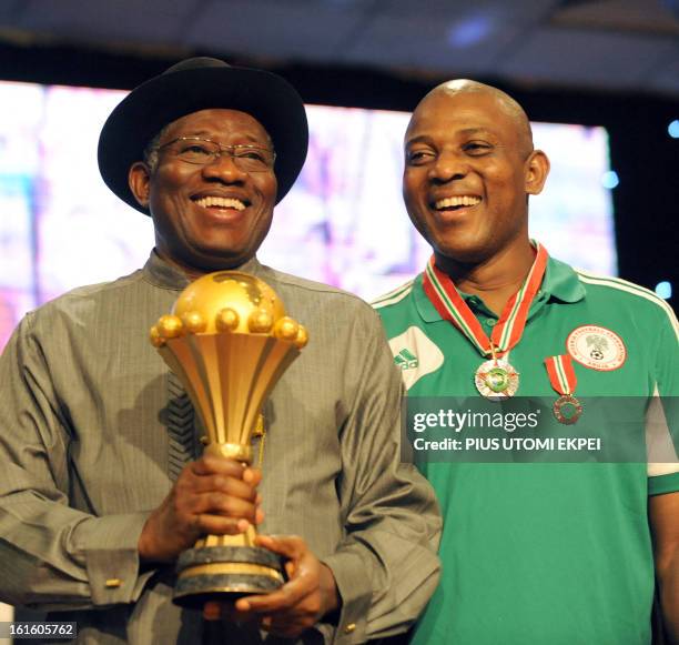 Coach of Nigerian football team Stephen Keshi poses with President Goodluck Jonathan who holds the 2013 African Cup of Nations trophy during the...