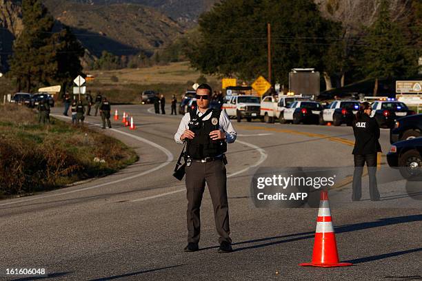 Law enforcement officers monitor a police roadblock on Highway 38, which leads to the Big Bear Lake, California, as a standoff with the former Los...