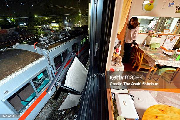 Resident stands by a window of her apartment where the balcony was destoryed by the derailed Sanyo Electric Railway Co. Train after a collision with...