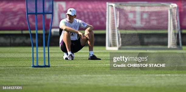 Bayern Munich's German head coach Thomas Tuchel sits on a ball as he attends a public training session at the club's grounds in Munich, southern...