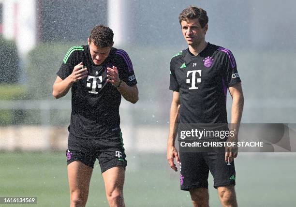 Bayern Munich's French defender Benjamin Pavard reacts to a water shower next to his teammate Bayern Munich's German forward Thomas Mueller during a...