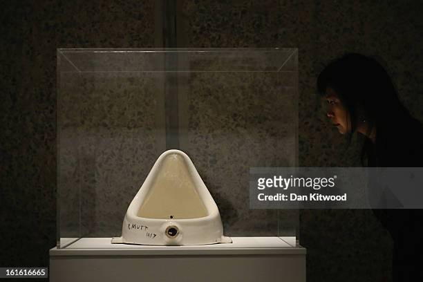 Woman looks at a piece of work entitled 'Fountain' by Marcel Duchamp during a press preview of 'The Bride and the Bachelors' exhibition at the...