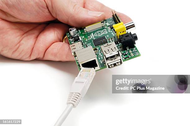 Detail of hands inserting an Ethernet cable into a Raspberry Pi Model B single-board computer photographed on white, taken on June 14, 2012.