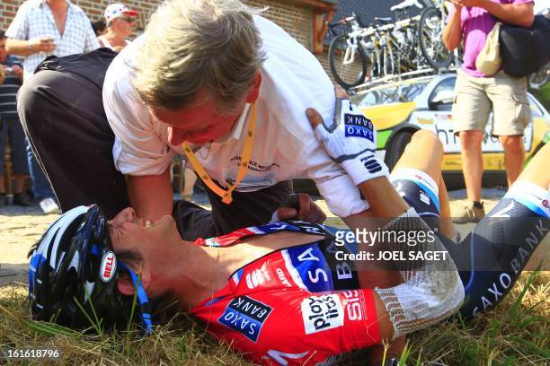 Luxembourg's Frank Schleck receives medical assistance from Tour de France doctor Gerard Porte after he crashed in the first France's cobblestones...