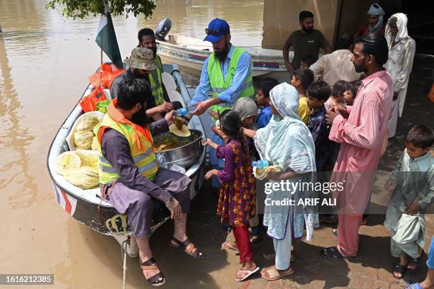 Volunteers distribute food to people in the flood affected area of Bhikhiwind village in Kasur on August 22, 2023. Around 100,000 people have been...