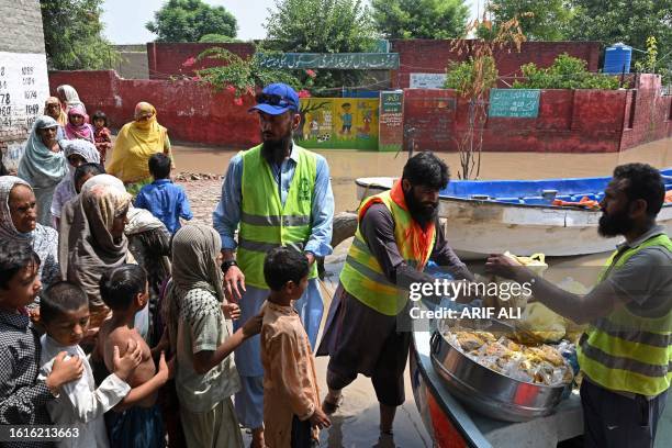 Volunteers distribute food to people in the flood affected area of Bhikhiwind village in Kasur on August 22, 2023. Around 100,000 people have been...