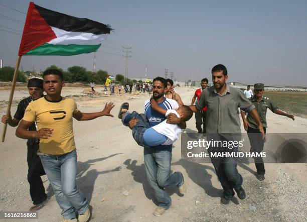 Palestinian men rush with a wounded boy after he was shot while waiting for released relatives from Israeli prisons, at the Erez crossing, northern...