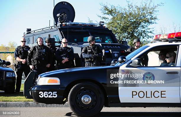 Members of a SWAT Team watch from the roadside as police lead a convoy of of vehicles, including the hearse carrying the body of slain Riverside...