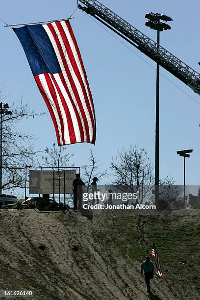 An American flag hanging from a fire department vehicle stands in honor outside the funeral for Riverside police Officer Michael Crain at Grove...