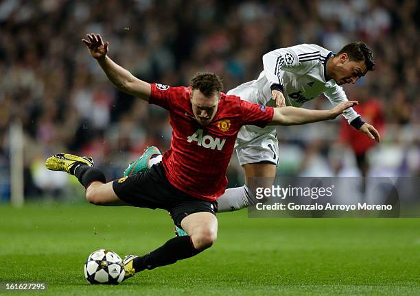 Mesut Ozil of Real Madrid clashes with Phil Jones of Manchester United during the UEFA Champions League Round of 16 first leg match between Real...