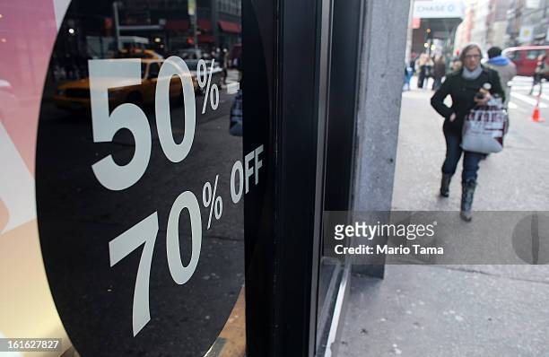 Woman carries a shopping bag past a store with a sale sign in the window in Manhattan on February 13, 2013 in New York City. The Commerce Department...