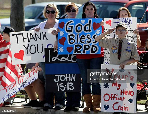 Boy salutes the procession of police vehicles leaving the funeral service for Riverside police Officer Michael Crain at Grove Community Church in...