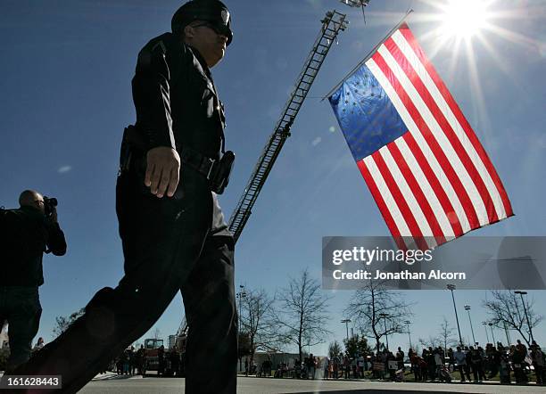 Police officer walks past a flag hanging from a fire truck at the funeral service for Riverside police Officer Michael Crain at Grove Community...