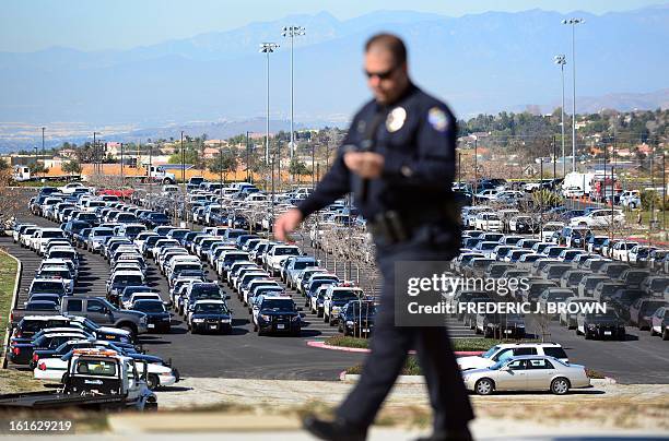 Policeman walks past a parking lot full of police vehicles as police officers, friends and family attend a memorial service for slain Riverside...