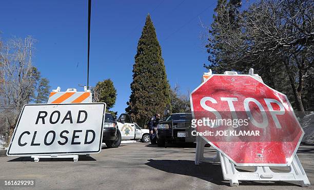 Law enforcement officers watch a roadblock as they continue the closure of Highway 38 at Angelus Oaks, California, on February 13, 2013. A former US...