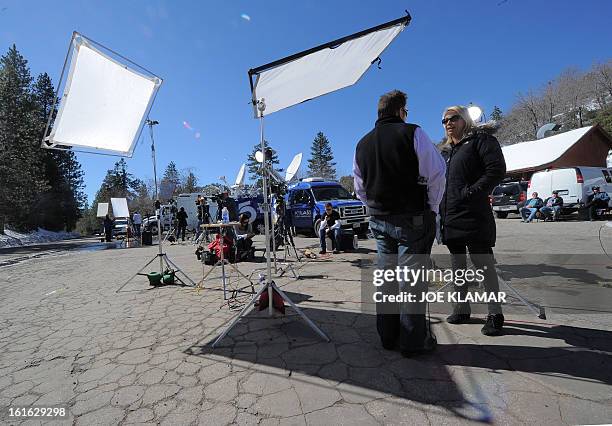 Journalists wait near a roadblock of Highway 38 at Angelus Oaks, California, on February 13, 2013. A former US cop wanted for at least three murders...