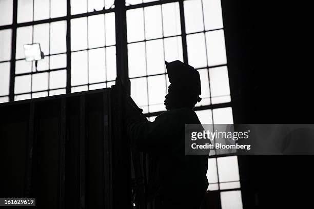 The silhouette of Langley Ronnie, a Capsys Corp. Employee, is seen MIG welding the frame of a modular housing unit at the Brooklyn Navy Yard in the...