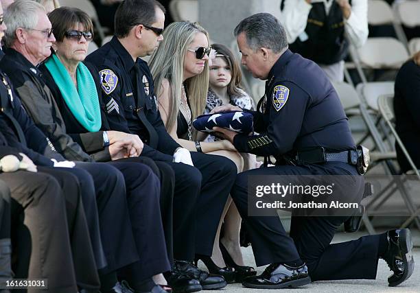 Riverside Police Chief Sergio Diaz presents the flag to Regina Crain, wife of officer Officer Michael Crain, during his committal ceremony at...