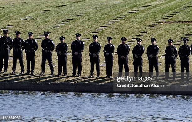 Police officers stand at attention during the committal ceremony of officer Michael Crain at Riverside National Cemetery on February 13, 2013 in...