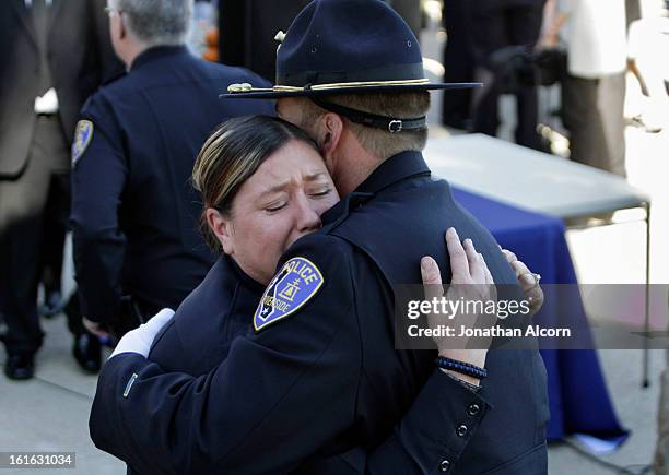 Riverside police officers embrace following the committal ceremony of officer Michael Crain at Riverside National Cemetery on February 13, 2013 in...