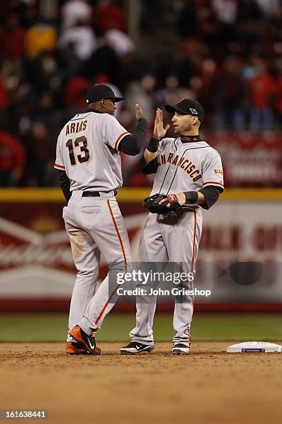 Joaquin Arias and Marco Scutaro of the San Francisco Giants celebrate defeating the Cincinnati Reds in Game 4 of the National League Division Series...