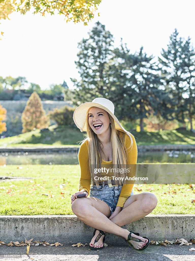 Laughing young woman in park with moblie device