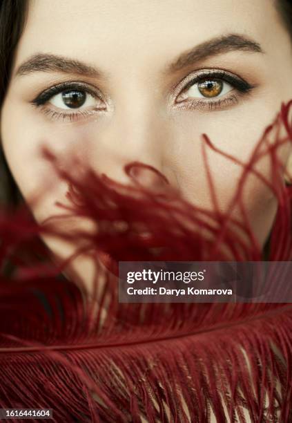 heterochromia, close up portrait of beautiful woman with different eyes. red lipstick on lips and red feather, concept of tenderness and female issues with copy space. - ladies day stock pictures, royalty-free photos & images