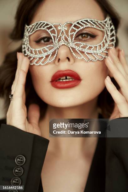 a beautiful woman in a masquerade mask and stage makeup. a close up woman portrait in black jacket and with red lips . - fiesta posterior stock pictures, royalty-free photos & images