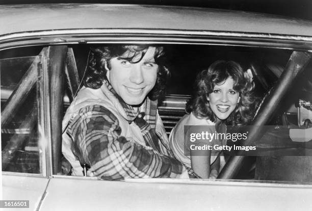American actors John Travolta and Nancy Allen pose in a car on the set of the film, 'Carrie,' directed by Brian De Palma, 1976.