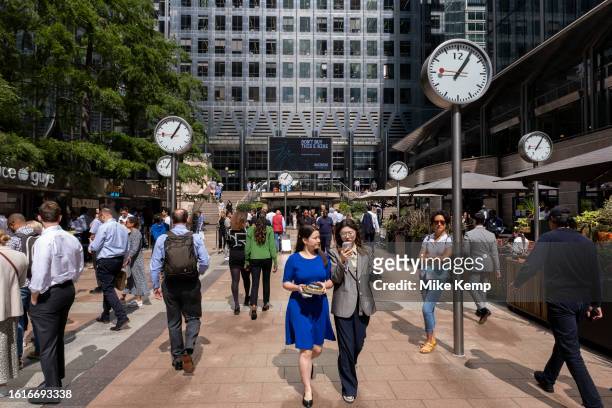 City workers walk under 'Six Public Clocks', a sculpture by Konstantin Grcic at Nash Court in Reuters Plaza at the base of One Canada Square, at the...