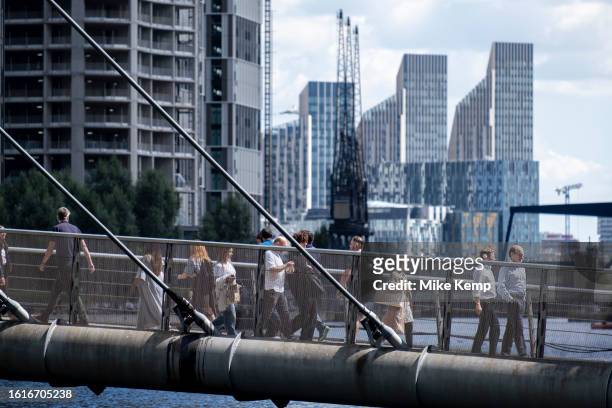 People and workers crossing the South Quay Footbridge in the heart of Canary Wharf financial district as new apartment high rise buildings can be...