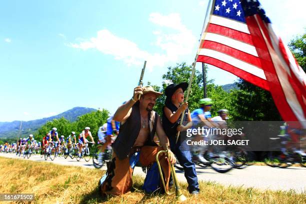 Fans dressed as cow-boys wave a US flag as the pack rides on July 14, 2010 during the 179 km and 10th stage of the 2010 Tour de France cycling race...