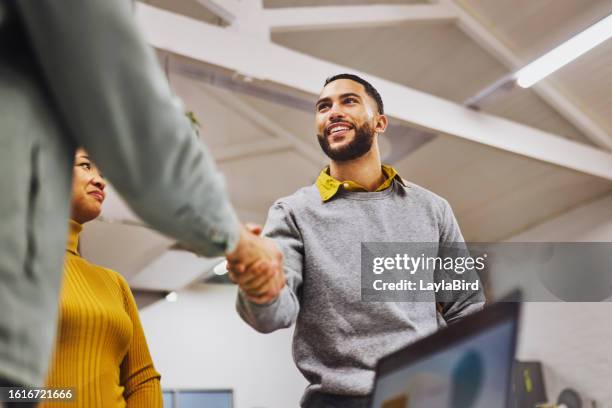 low angle view of cheerful executive shaking hands with colleague in office - greeting stock pictures, royalty-free photos & images