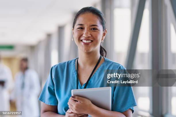 close-up of female nurse with digital tablet, smiling at camera in corridor - een dag uit het leven serie stockfoto's en -beelden
