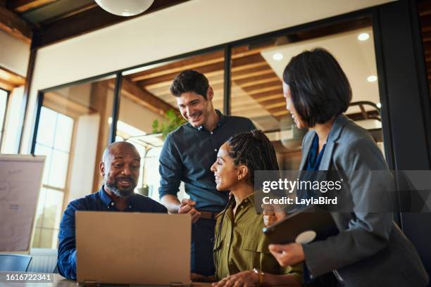 diverse group of entrepreneurs smiling cheerfully and using laptop in boardroom - teamwork stockfoto's en -beelden
