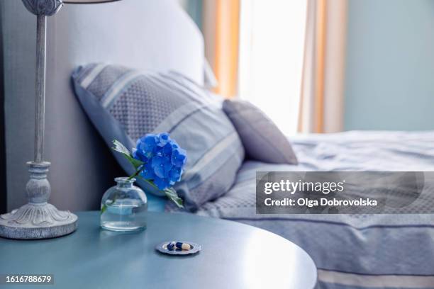 bedside table with medicine and a vase on it against a bed in a bedroom - domestic room stock pictures, royalty-free photos & images