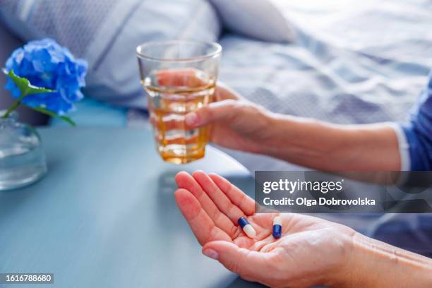 side view of woman's hands holding medicine and a glass of water - servant stock pictures, royalty-free photos & images